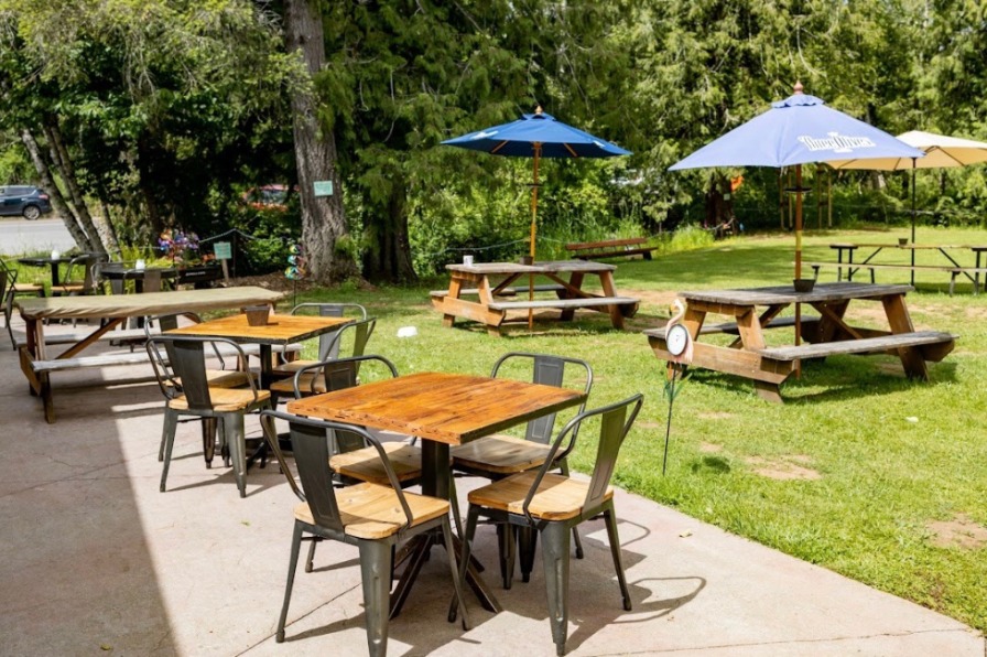 Fir Valley Pour House Wood tables outside with blue umbrellas