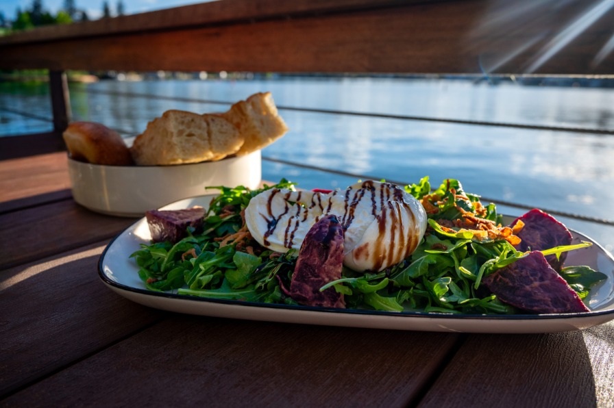 Manns On The Lake A plate of food sits on a wooden table with a lake behind.