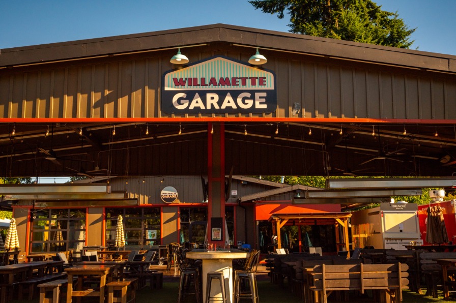 Willamette Garage in West Linn A building with tables below a brown sign.