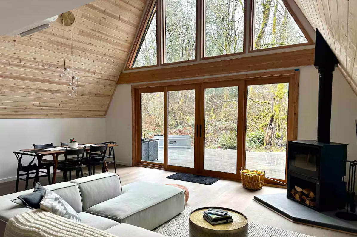A room with a grey couch and big windows
