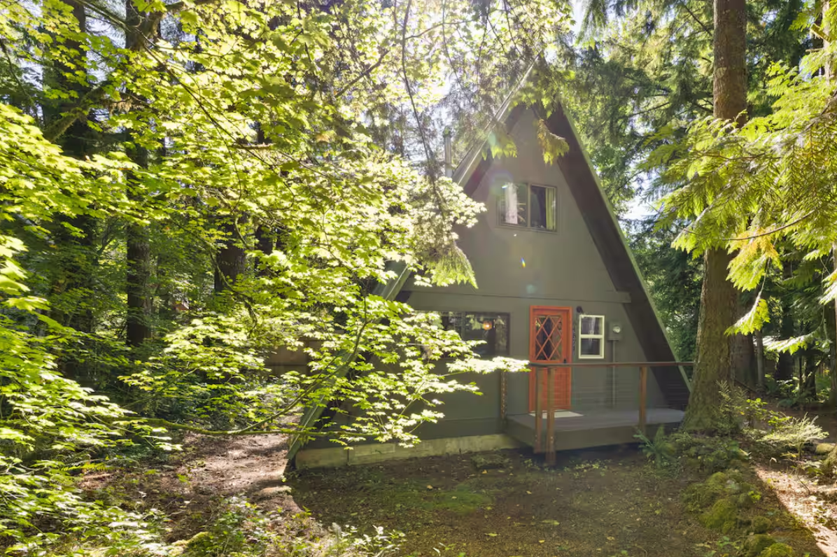 A green painted aframe house surrounded by trees