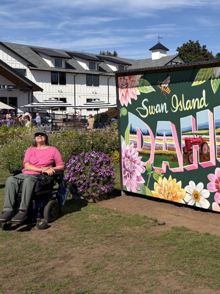 A person in a pink shirt in a wheelchair next to a sign