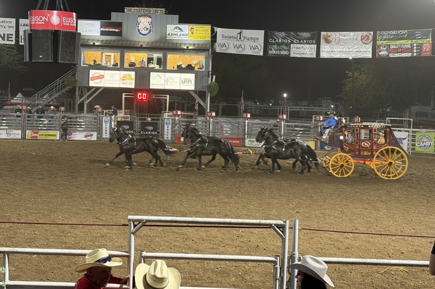 The Canby Rodeo A red stagecoach is pulled behind black horses