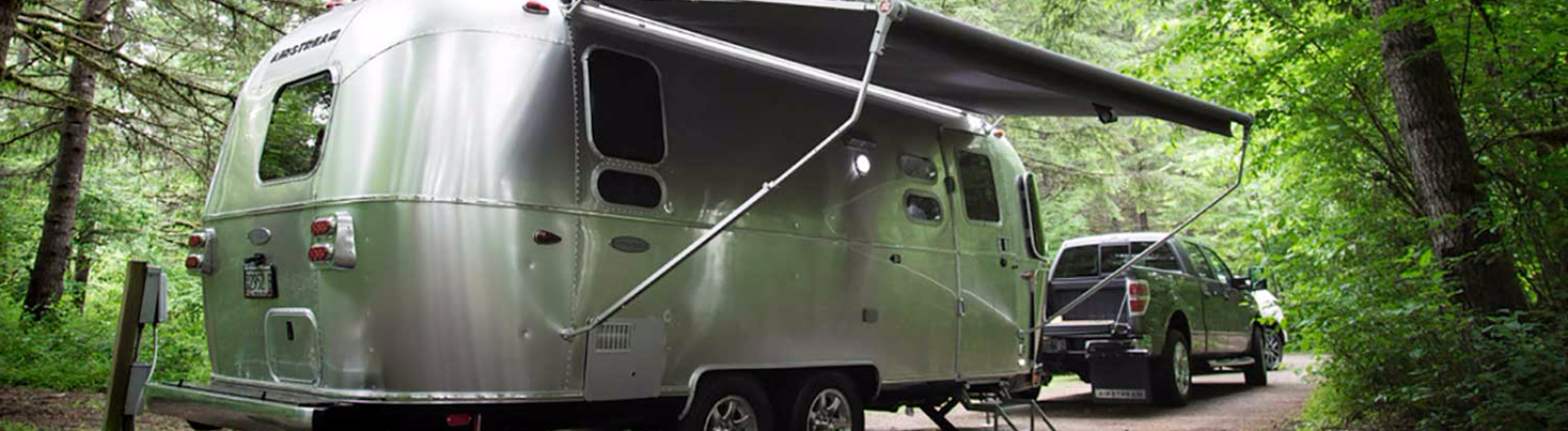 Silver Airstream Trailer at a forested campsite in Oregon's Mt. Hood Territory