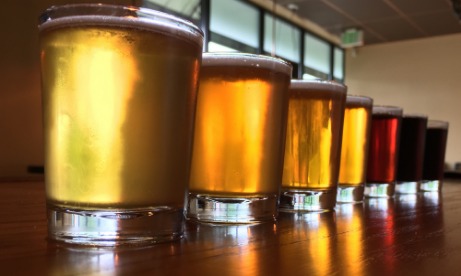 Coin Toss Brewing beer lineup of seven glasses from pale, to amber, to red, to very dark on taproom bar