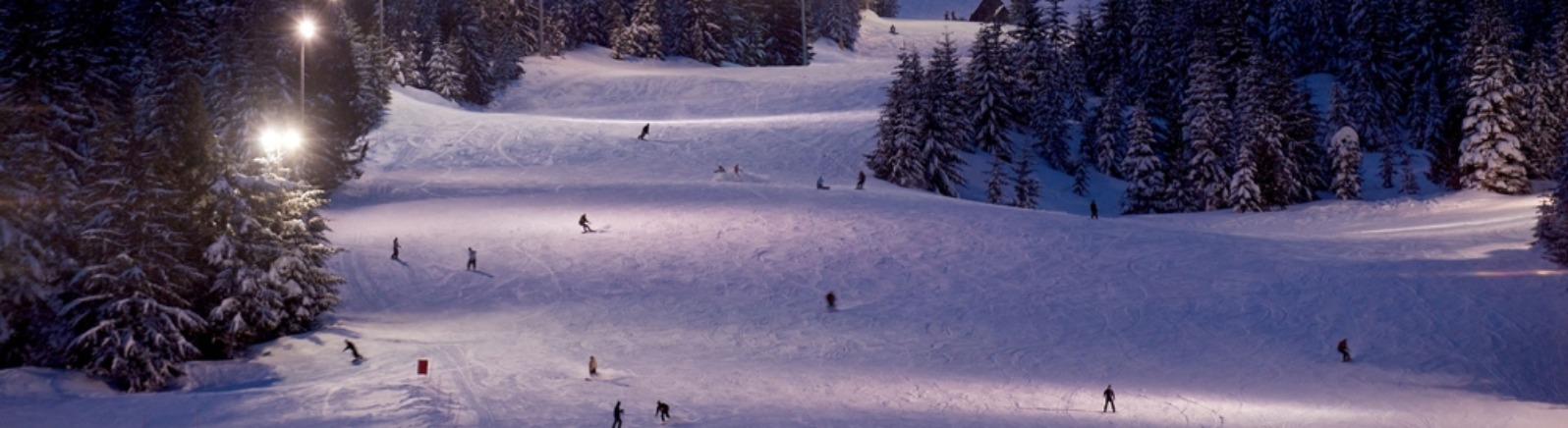 Large floodlights illuminate the upper bowl and lower ski run as skiers and boarders enjoy night skiing at Mt. Hood Skibowl