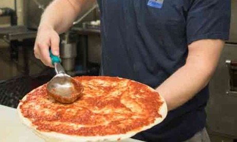 Ivy Bear Pizzeria owner Scott adding sauce to pizza dough 